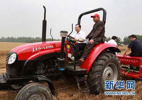 6月10日，在河南省許昌縣陳曹鄉(xiāng)后孫汪村高產(chǎn)小麥?zhǔn)痉秴^(qū)，中共中央政治局常委、國務(wù)院總理溫家寶登上一臺“東方紅”牌拖拉機(jī)的駕駛室，在司機(jī)的指導(dǎo)下掛擋、加油，緊握方向盤，穩(wěn)穩(wěn)地駕駛著，在剛剛收割的麥地里深耕、施肥，種下秋玉米。新華社記者龐興雷攝 