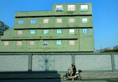 圖片說明：彩色噴繪的窗戶裝點著灰色水泥外墻，荒誕而醒目。