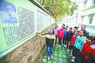 上圖：學(xué)校文化墻前，小講解員講述開國將軍杜義德的故事。記者何曉剛 攝