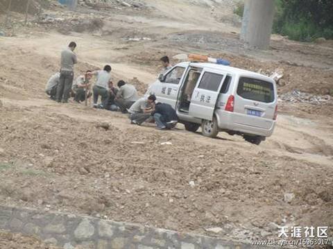 陜AWK707的西安城管執(zhí)法車和6名穿制服的城管，手持棍棒，在郊外毆打兩名倒地男子。 