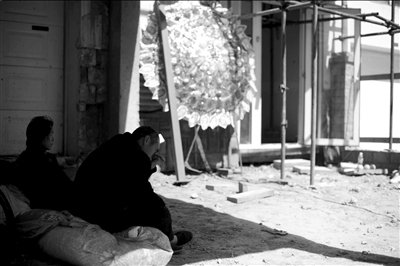 死者的哥哥嫂子坐在高虎家門前，低頭抹淚