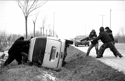 一輛轎車側翻在密云某路段溝內，眾人合力拉車。本報記者王苡萱攝