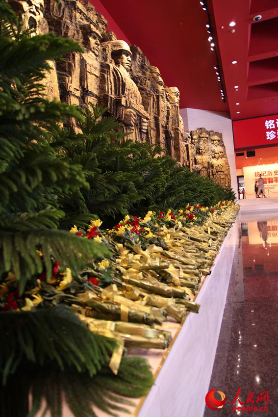 紀(jì)念館門(mén)廳的《銅墻鐵壁》雕塑墻，和人們獻(xiàn)上的花。邱越攝